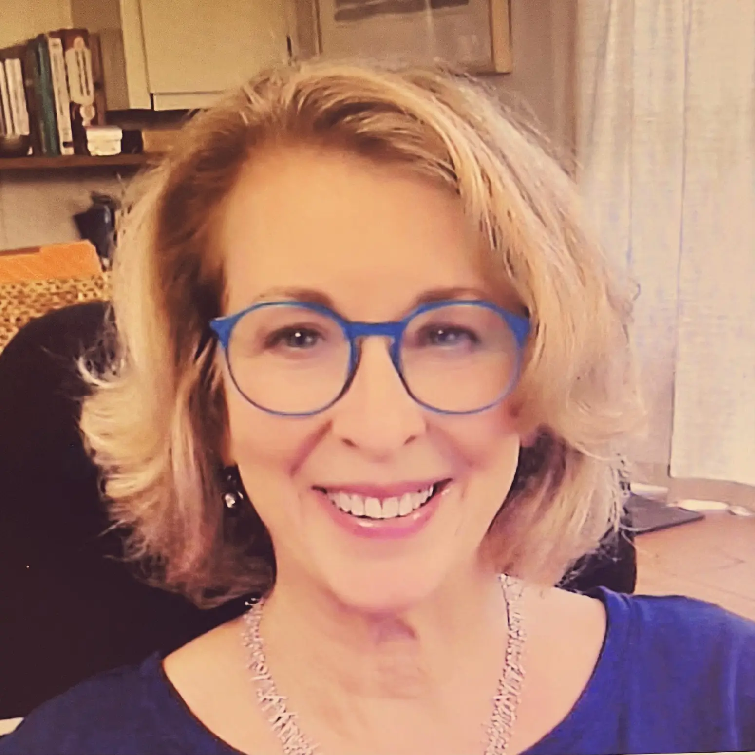 Close-up headshot of Carol Miles, MSW, LCSW, an EMDRIA Approved Trainer, wearing blue glasses and smiling in her therapy office in Covington, LA (serving areas 70433, 70434, and 70435)
